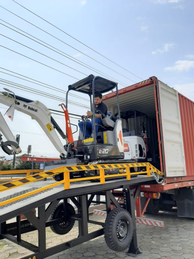 Operador descendo um Bobcat® da Rampa Niveladora Móvel de um contêiner de exportação/importação.